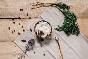 flat lay. fresh herbs, farmer cottage cheese in a ceramic bowl with a spoon and berries on a wooden background