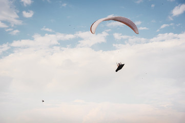 Alone paraglider flying in the blue sky against the background of clouds. Paragliding in the sky on...