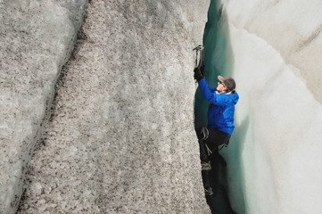 A free climber without insurance with two ice axes rises from a crack in the glacier. Free climbing...