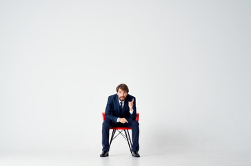 business man sitting on a red chair on a light background talks office