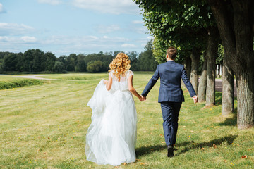 Bride and groom running in green park. Back of bride and groom. Wedding day in the park