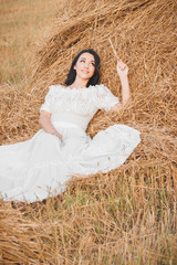 Beautiful young woman on the dried haystack