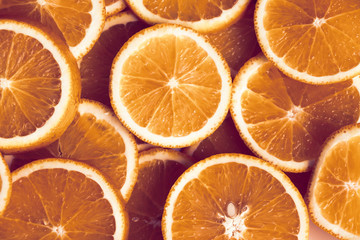 Many bright juicy orange fruits slices, cuts, halves,  Top view. Orange color background.. Toned.