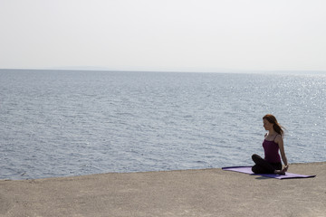 Young attractive woman doing yoga outdoors. Landscape of the river bank and young woman in yoga pose practising