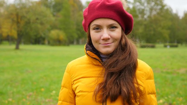 Portrait of young woman in red french beret in autumn park