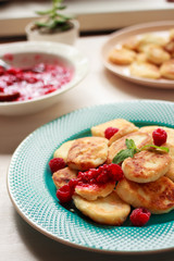 Traditional Russian dessert syrniki with fresh raspberries on a blue plate