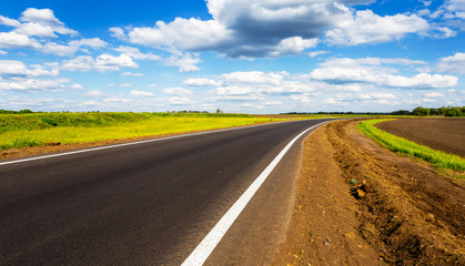 Fototapeta premium asphalt road turn under a blue cloudy sky