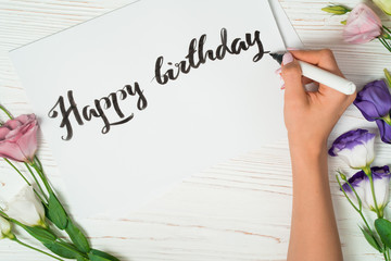 Happy birthday congratulations. Calligrapher writes with black ink on white card. Calligraphy....