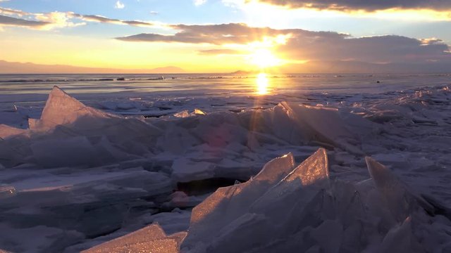 Dolly shot of gorgeous sunset over small icebergs and icicles in the frozen lake