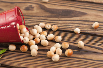Raw olives poured out of red metal bucket on old rustic wooden table