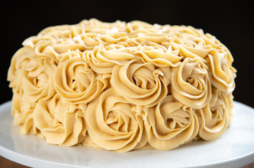 Close up of a pumpkin spice cake with butterscotch frosting in rosettes.