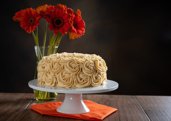 Pumpkin spice cake with butterscotch frosting with fall flowers.