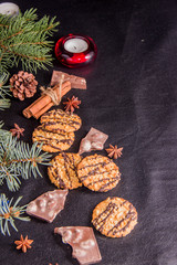 Christmas tree branches, biscuits stars blue cinnamon sticks on a black leather background with a place for the text