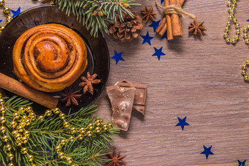 Sweet cinnamon pastry on a wooden background chocolate chips with Christmas-tree decorations and beads and stars