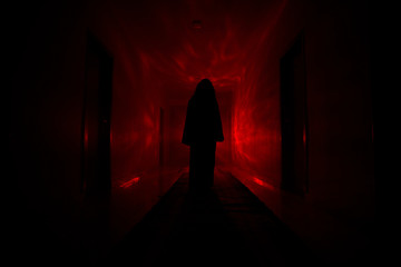 Creepy silhouette in the dark abandoned building. Dark corridor with cabinet doors and lights with...