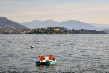 Barca per turisti sul lago con isola e montagne sullo sfondo, Lago Maggiore, Isola dei Pescatori, Italia