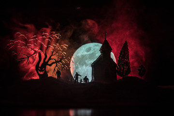 Scary view of zombies at cemetery dead tree, moon, church and spooky cloudy sky with fog, Horror...