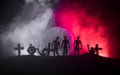 Scary view of zombies at cemetery dead tree, moon, church and spooky cloudy sky with fog, Horror Halloween concept.