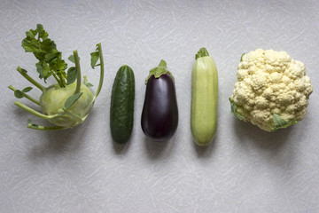 Kohlrabi cabbage, cucumber, eggplant, zuchinni and cauliflower in a ascending row  on the white background. Healthy organic food from the garden