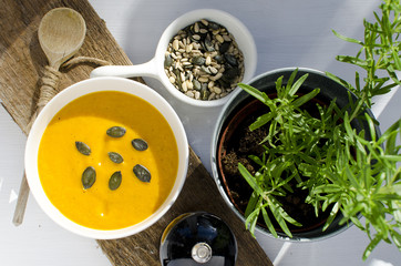 Creamy pumpkin soup with pip and spoun on wooden board
