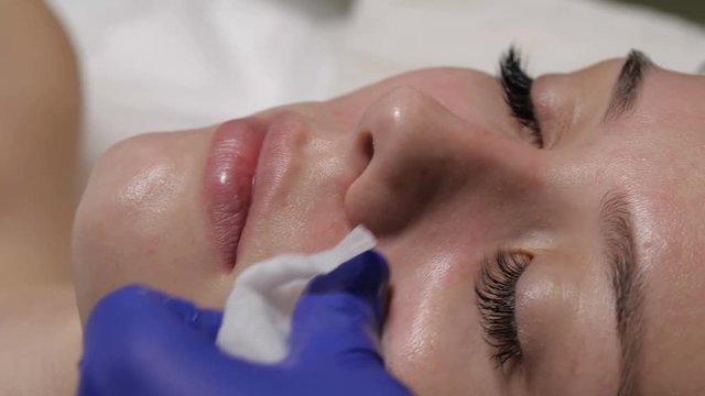 woman cosmetologist cleanses the face skin