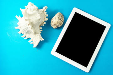 tablet, seashells, blue  background, concept of vacation, relaxation, technology