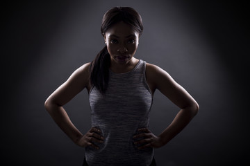 Silhouette of black female in an angry pose or portrait of an athlete concentrating for an extreme sport competition. The face is in shadow to portray anger or rage.