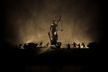 War - no justice concept. Military silhouettes fighting scene and The Statue of Justice on a dark...