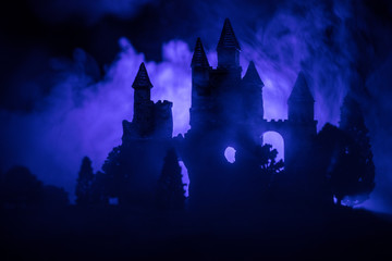 Mysterious medieval castle in a misty full moon. Abandoned gothic style old castle at night