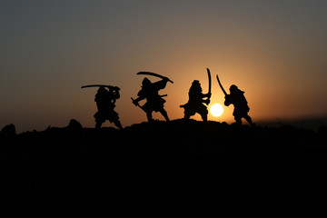 Fototapeta na wymiar Silhouette of two samurais in duel. Picture with two samurais and sunset sky. Selective focus