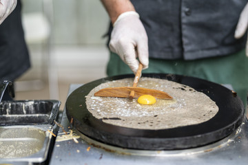 Cooking a salty crepe with ham, egg and cheese, a nice hand made preparation in the pan, traditional food with amazing flavors