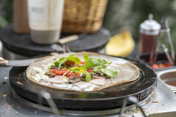 Cooking a salty crepe with lettuce, tomatoes and vegetables, a nice hand made preparation in the pan, traditional food with amazing flavors