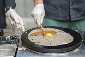 Cooking a salty crepe with ham, egg and cheese, a nice hand made preparation in the pan, traditional food with amazing flavors