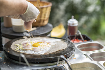 Cooking a salty crepe with ham, egg and cheese, a nice hand made preparation in the pan, traditional food with amazing flavors