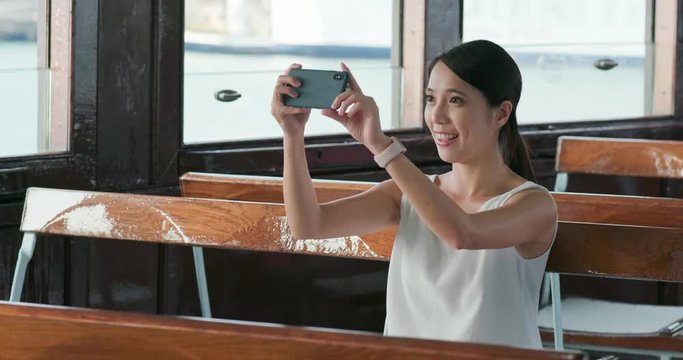 Woman taking photo on cellphone on ferry