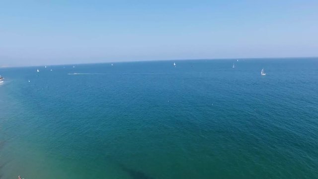 Tilt reveal of the Pacific Ocean from a beach in California filled with sailboats and surfers