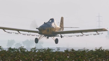 Crop duster spraying chemicals over a cotton field - slow motion