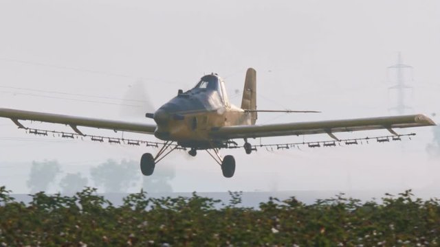 Crop duster spraying chemicals over a cotton field - slow motion