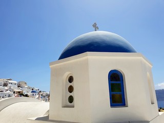 Fototapeta na wymiar Traditional blue dome church in the beautiful city or Oia, Santorini against blue sky