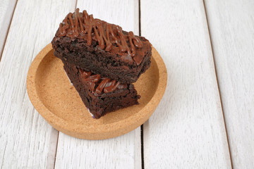 Chocolate brownie with melted chocolate on a wooden plate