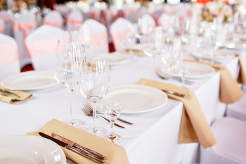 Table at a luxury wedding reception. Beautiful flowers on the table. Serving dishes, glass glasses, waiters work,