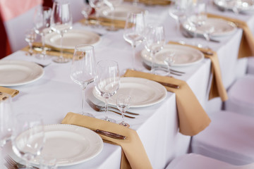 Table at a luxury wedding reception. Beautiful flowers on the table. Serving dishes, glass glasses, waiters work,