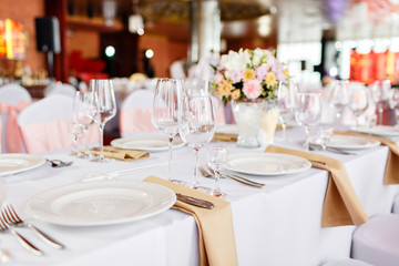 Table at a luxury wedding reception. Beautiful flowers on the table. Serving dishes, glass glasses, waiters work,
