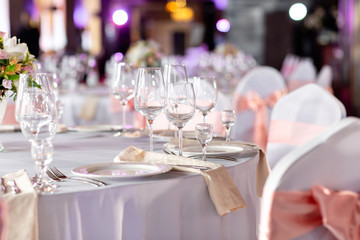 Round table at a luxury wedding reception. Beautiful flowers on the table. Serving dishes, glass glasses, waiters work,