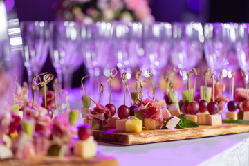 the buffet at the reception. Glasses of wine and champagne. Assortment of canapes on wooden board....
