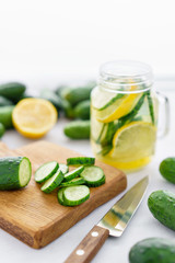 focus on cucumber slices. Summer cocktail cucumber lemonade. Refreshing water with cucumber, mint and lemon on grey background. Healthy drink and detox concept. Copy space