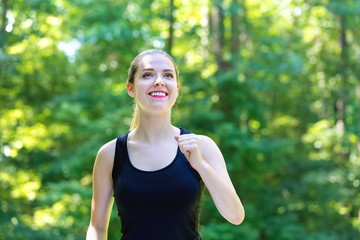 Athletic young woman jogging on a bright summer day in the forest
