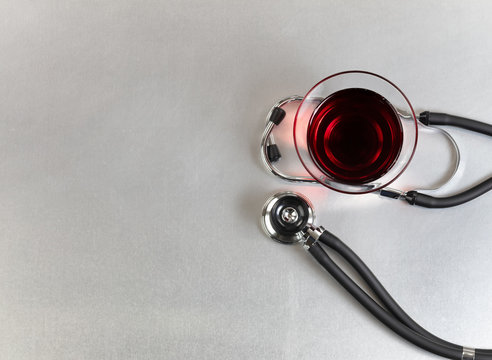 Overhead view of alternative medicine with red wine and stethoscope on stainless steel table