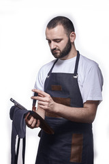 one young chef in uniform, holding set of knives. white background, studio shot.