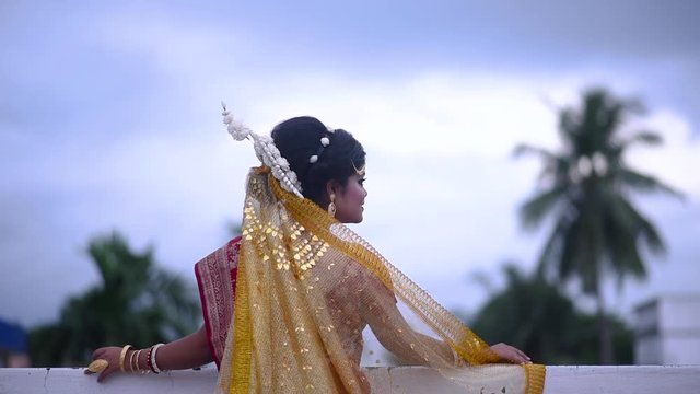 Sad and upset Indian Bengali bride looking at dark cloudy sky on monsoon evening